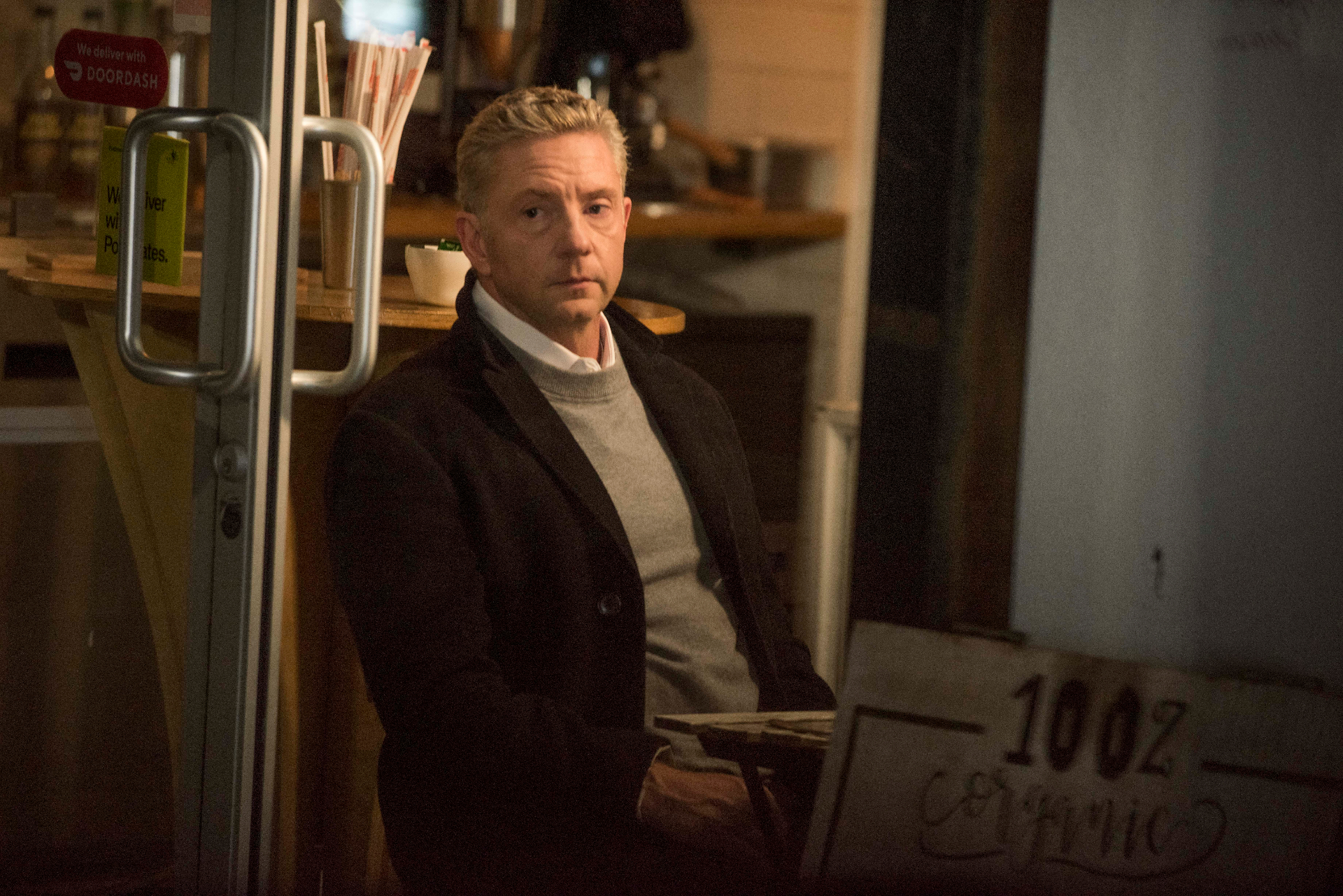 Tommy framed in a café doorway at night.