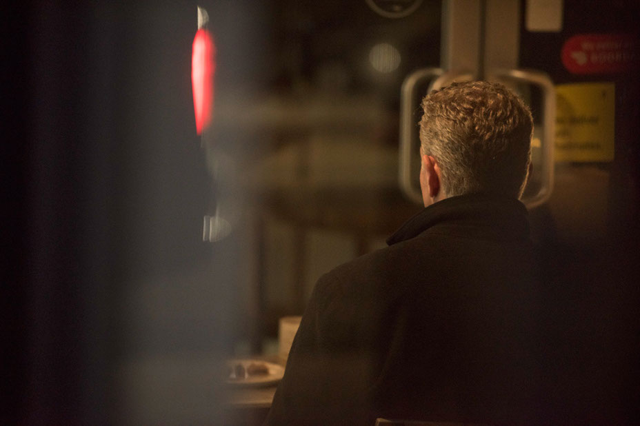 Tommy alone at a diner counter under a red light.