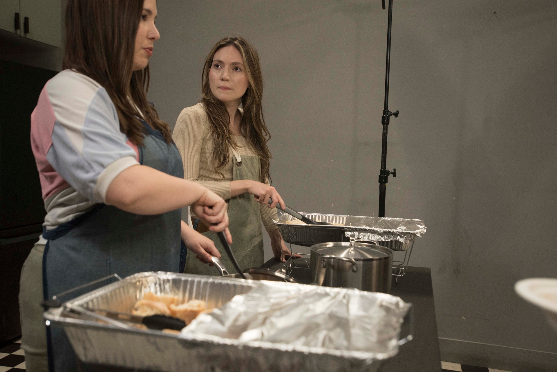 Two women in aprons working a community kitchen line.
