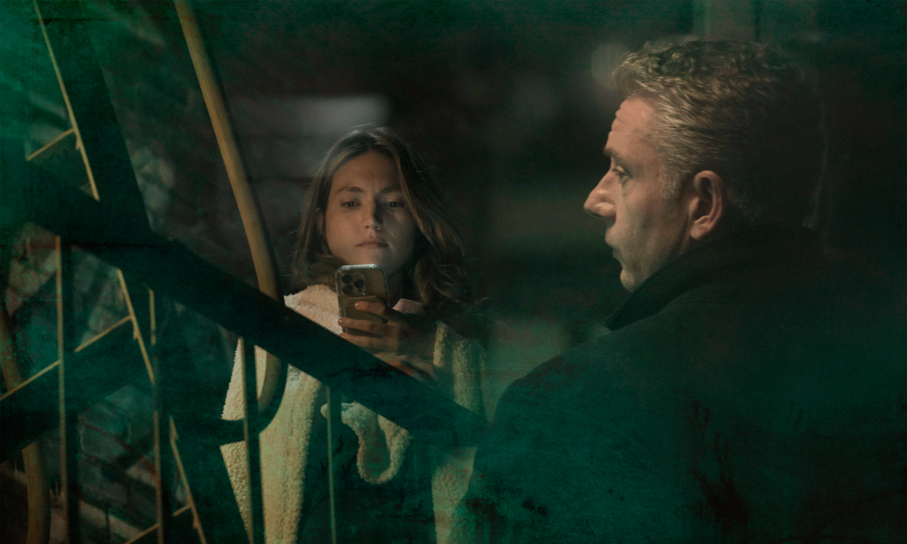 Tommy and Amanda separated by glass at night, a phone held between them.